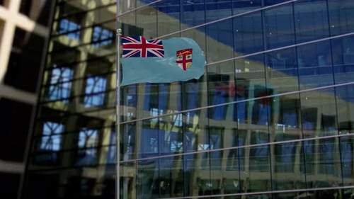 Fiji Flag Waving on Flagpole Against Modern Building