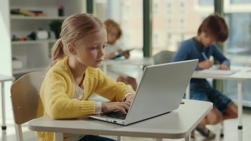 Side View of the Girl Student Using Laptop for Studying Purposes at School in the Class and Other