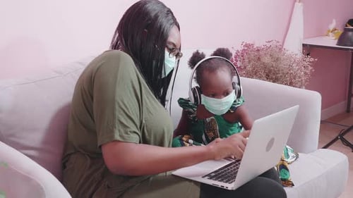 Woman and Child on Couch Looking at Laptop