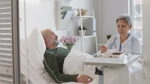 Medical Professional Assists Mature Patient With Eating