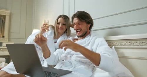 Couple Celebrating Good News on Laptop in Hotel Bed