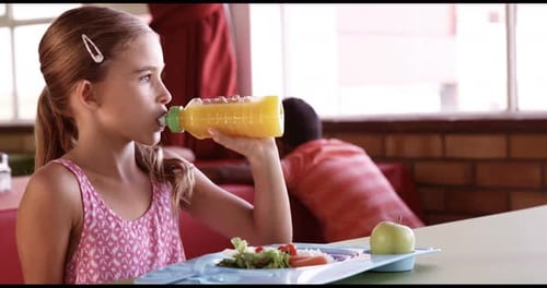 Girl Drinks Juice At School Cafeteria Lunch Table