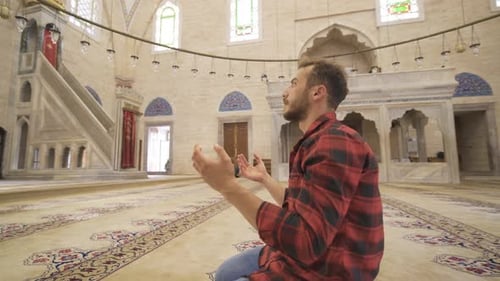 Young muslim man praying in historical mosque.