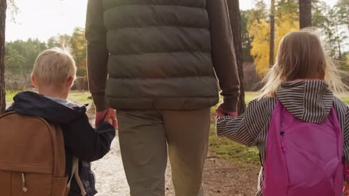Unrecognizable Father Walking with Children in Forest