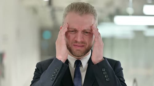 Frustrated Man Massages Temples in Pain