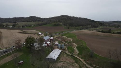 Ansicht der Farm im Tal mit Autobahn, die an den Gebäuden vorbeiführt. Berge auf jeder Seite.