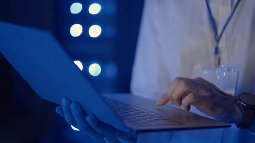 Man Working on Laptop in Server Room at Night