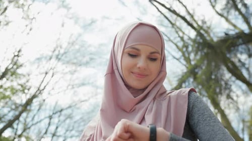 Woman in Headscarf Checks Smart Watch
