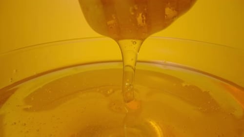 Honey Dipper Drizzling Sweet Honey in a Bowl