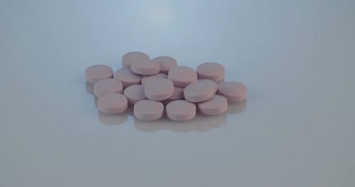 Pile of Pink Pills on Light Gray Surface
