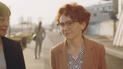 Two Business Women Walking and Talking Outside