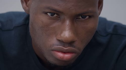 Thoughtful worried young african man rubbing his hands