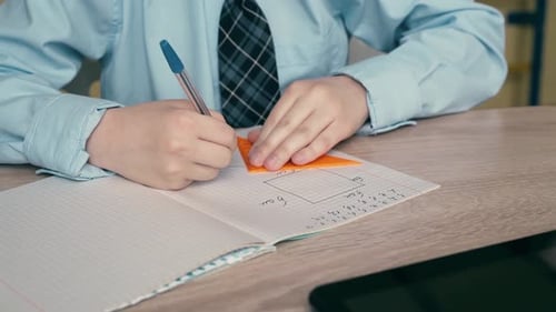 Student Drawing Geometry Shapes in Notebook at School