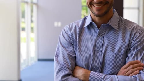 Male business executive standing with arms crossed in office