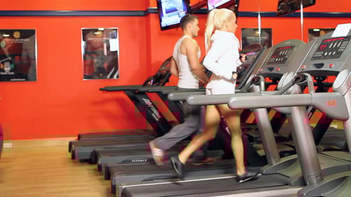 Man and Woman Running on Treadmills at Gym