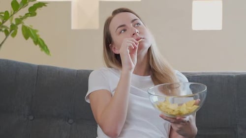 Woman Eating Potato Chips on Sofa