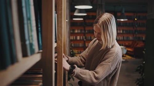 Jovem estudante chegando às estantes de livros na biblioteca e escolhendo o rastreamento de informações de leitura de livros