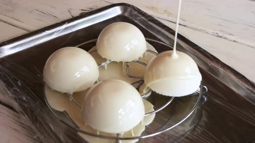 Glaze Being Poured over Round Dessert Cakes