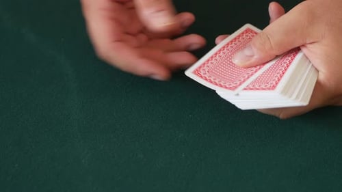 Nahaufnahme der Hände eines Casino-Dealers, während er Spielkarten ausgibt und dann die Karten auf der Registerkarte auffängt