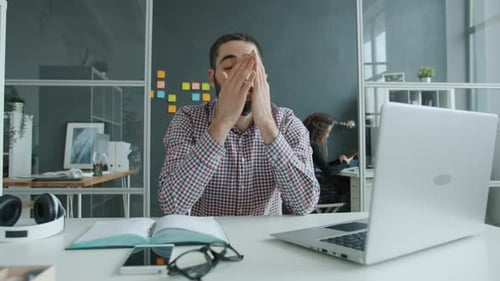 Man Tired at Desk in Office Typing on Laptop
