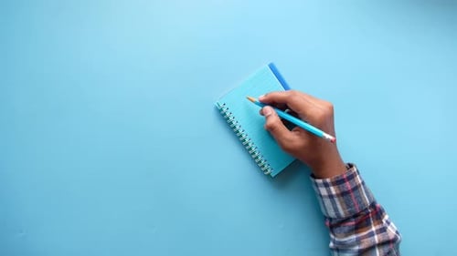 Top View of Man Hand Writing on Notepad