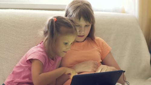 Girls Using Tablet Device Together on a Couch