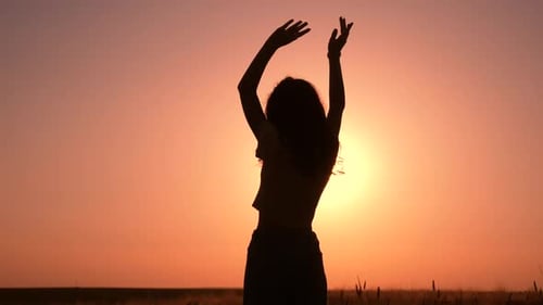 Girl standing in front of bright sunset
