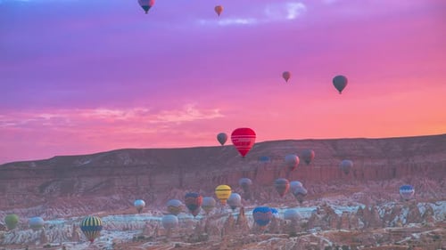 Landscape of Vibrant colorful balloons in pink sunrise in Goreme, Cappadocia, Turkey
