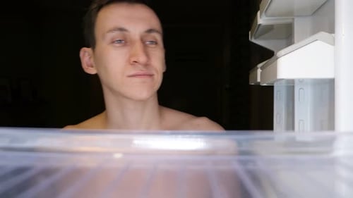 Tired Man Looking into Empty Refrigerator at Night