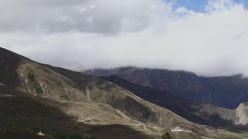Timelapse Clouds Swirl Over a Mountain Valley a Snowy Peak in the Distance