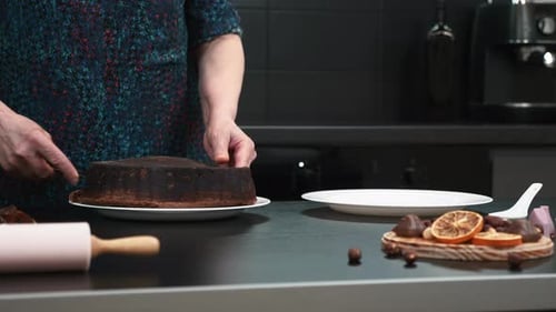 Adult Cuts Chocolate Cake in Dark Kitchen