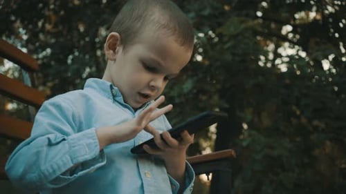 Kleiner Junge spielt Videospiele auf seinem Smartphone im Freien