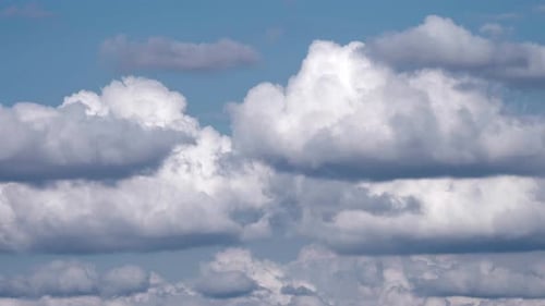Time lapse of white fluffy clouds over blue sky.