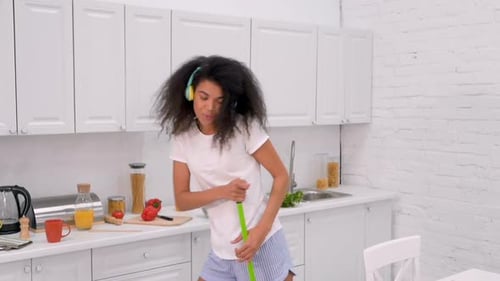 Woman Dancing with Mop in Kitchen