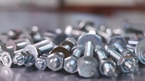 Slider Shot Video of Chrome Bolts and Nuts in a Chaotic Order Industrial Background