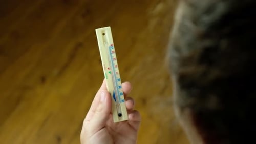 Frau überprüft die Temperatur im Haus Hohe Temperatur im Sommer