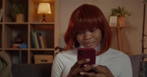 Crop View of Beautiful Woman Using Smartphone and Smiling While Sitting on Couch at Home