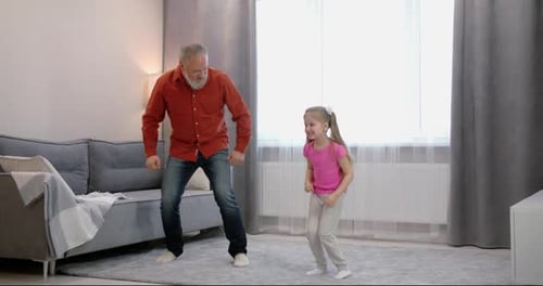 Grandfather and Granddaughter Dancing Together at Home