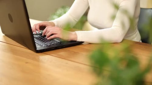 Woman Typing on Laptop at Wooden Desk