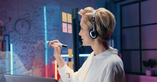 Femme chef de bureau dans un casque parlant avec des collègues sur un ordinateur portable, discutant avec eux de stratégie