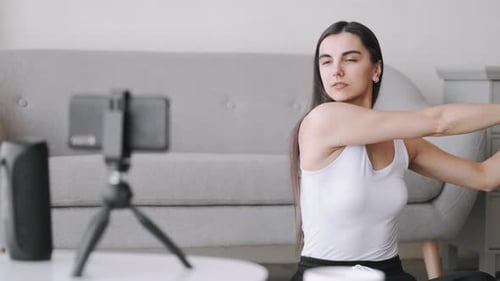 Young Woman Stretching Arms Filming Workout at Home