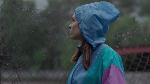 Pensive Woman in Blue Raincoat Stands Outdoors