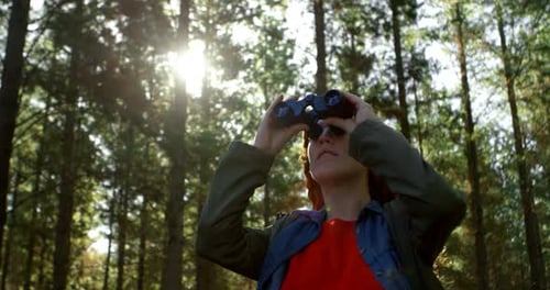 Woman looking through binoculars in the forest 4k