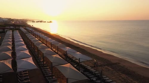 Top View of Sunbeds on Empty Sandy Beach at Sunset.