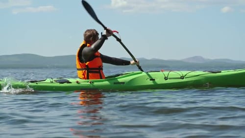 Adult Kayaking on Lake with Distant Mountains