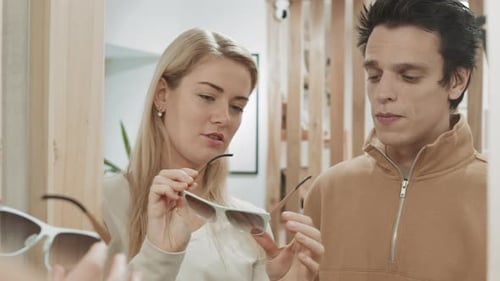 Woman Helping Husband Choosing Sunglasses
