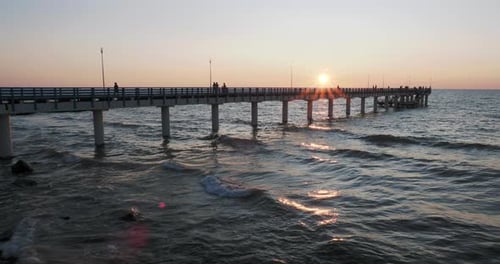 Silhouettes of People Walking on the Pier Against the Sunset. Local People Are Fishing, Tourists Are