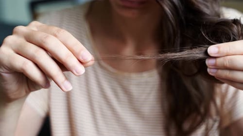 Woman Examining Split Ends on Dark Brown Hair