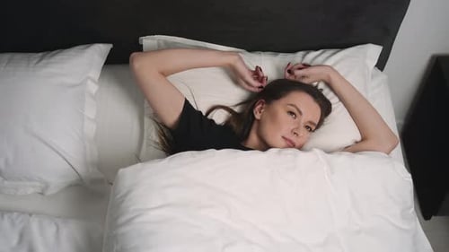 Woman Waking and Stretching in Comfortable White Bed