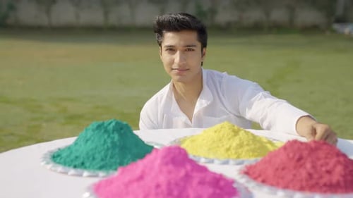 Man Smiling Next to Colorful Holi Powder